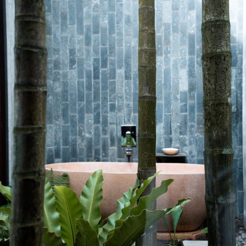 Baignoire extérieure entourée de végétation tropicale dans le jardin de l’hôtel Amber Kampot.