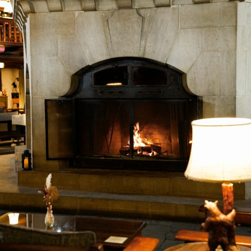 Salon du Fairmont Montebello avec cheminée en pierre allumée et mobilier chaleureux au Québec