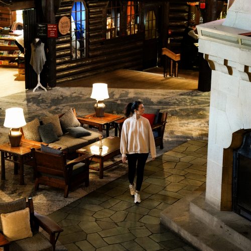 Personne marchant dans le hall principal du Fairmont Montebello, entre cheminée et salons en bois