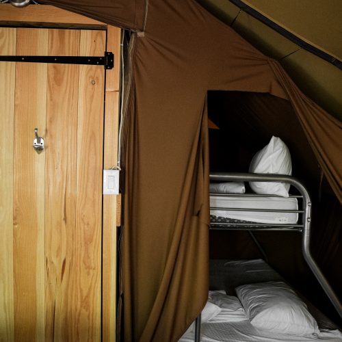 Lits superposés à l’intérieur d’une tente Huttopia, toile beige et mobilier en bois, hébergement nature à Sutton