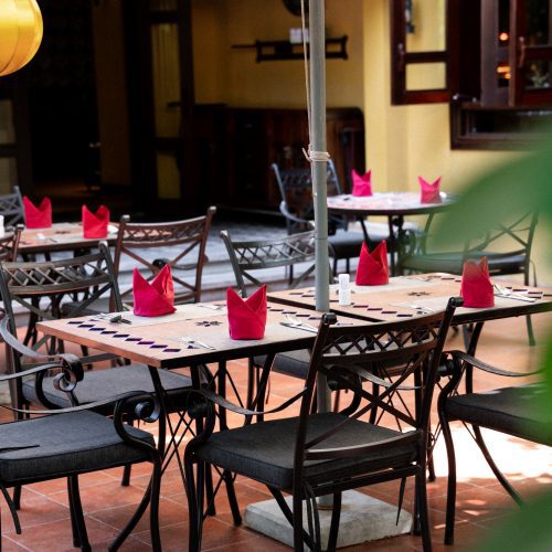 Terrasse du restaurant de La Siesta Hoi An avec tables dressées et serviettes rouges.