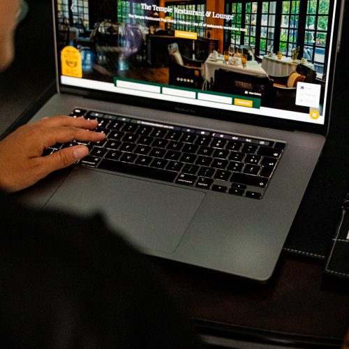 Personne utilisant un ordinateur portable affichant le site du restaurant de La Siesta Hoi An.