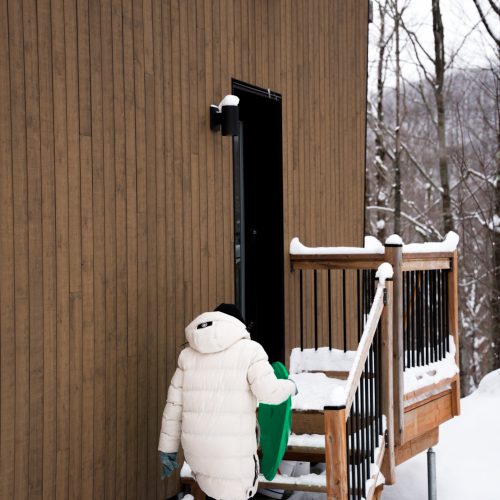 Personne montant les marches d’un chalet en bois du domaine Le Vertendre en hiver.