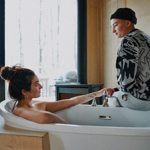 Personne prenant un bain dans un chalet pendant qu’une autre lui tient la main au Vert Tendre, au Québec