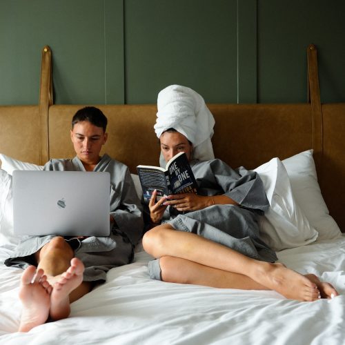 Deux voyageurs se reposent sur un lit super king-size dans la PHANA Suite King du Maison Hotel Bangkok.