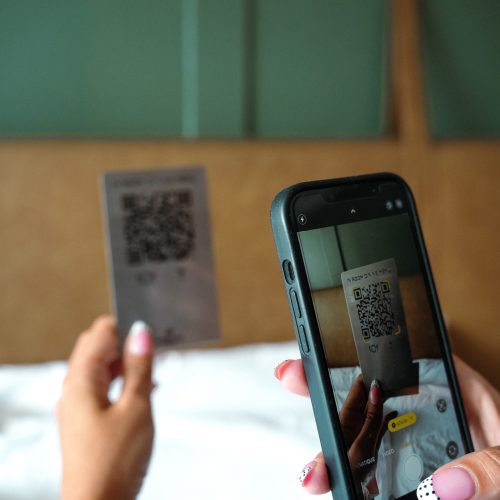 Un téléphone est utilisé pour scanner une carte QR code “In room dining menu” dans une chambre du Maison Hotel Bangkok.