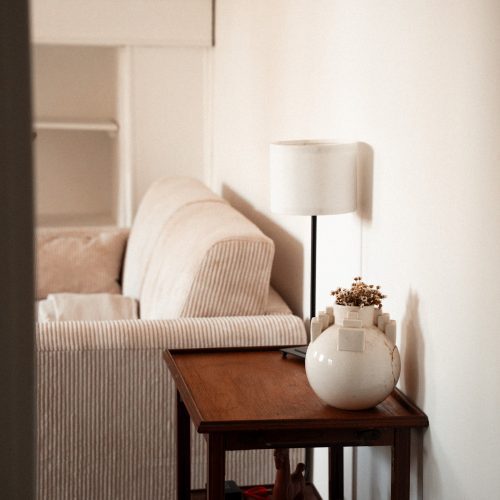 Coin salon dans un gîte du Mas Cantegril, avec table en bois, lampe et canapé clair.