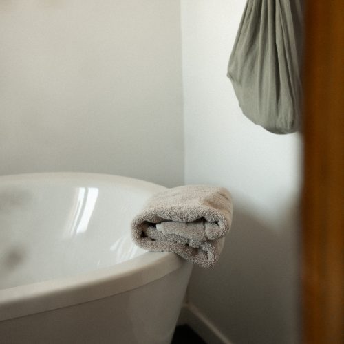 Baignoire dans la salle de bain d’un gîte du Mas Cantegril, avec serviette pliée et lumière douce.