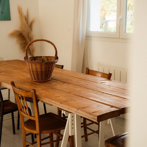 Table en bois et chaises dans la salle à manger d’un gîte du Mas Cantegril, espace lumineux et convivial.