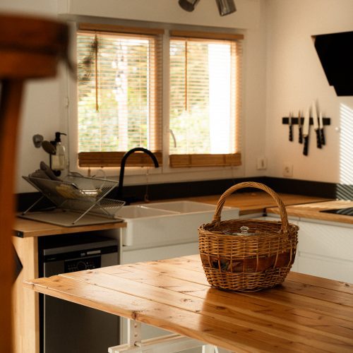 Table en bois avec panier dans la cuisine d’un gîte du Mas Cantegril, espace lumineux et fonctionnel.