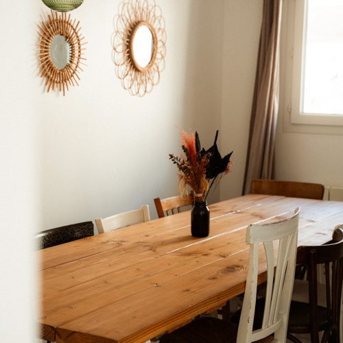 Salle à manger d’un gîte du Mas Cantegril avec grande table en bois, chaises et décoration murale.