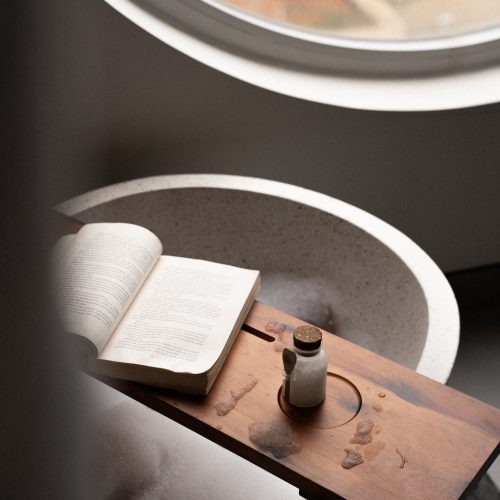 Livre ouvert posé sur un plateau en bois au-dessus d’une baignoire dans la suite de l’hôtel Meander Saigon.