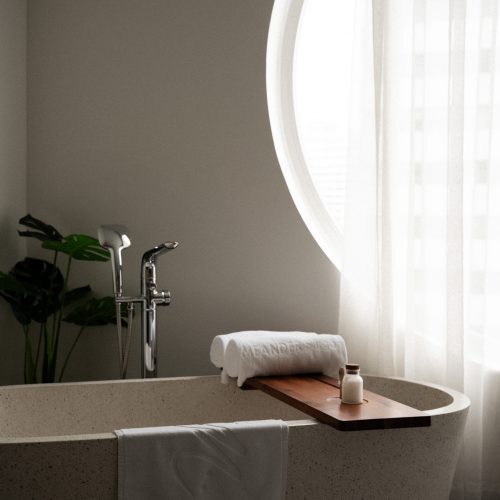 Baignoire installée près d’une grande fenêtre circulaire dans la suite de l’hôtel Meander Saigon.