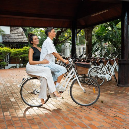 Deux personnes assises sur un vélo dans la cour intérieure du Parasol Blanc à Luang Prabang.