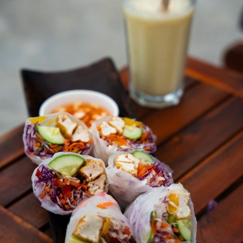 Rouleaux de printemps servis sur une table en bois avec une boisson au The Secret Garden Koh Rong.