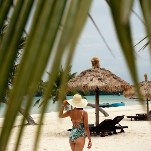 Personne marchant sur la plage devant des parasols en paille au The Secret Garden Koh Rong.