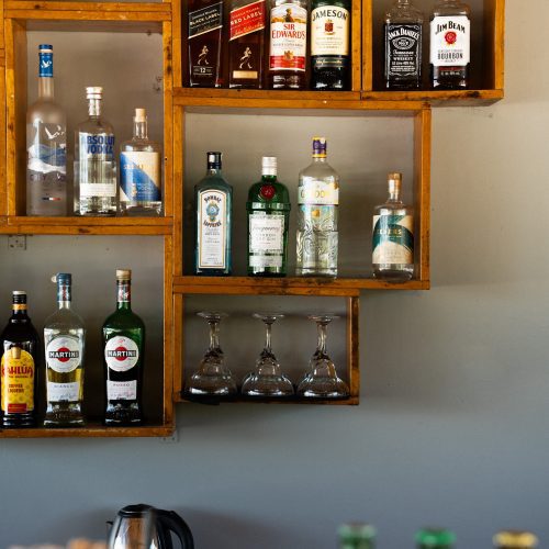 Étagères du bar au The Secret Garden Koh Rong avec bouteilles et verres, hôtel au Cambodge, photo chloeandaurore.