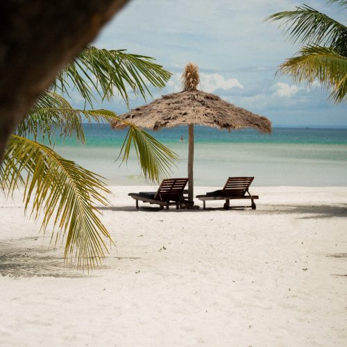 Transats sur la plage du The Secret Garden Koh Rong entourés de palmiers face à la mer, photo par chloeandaurore