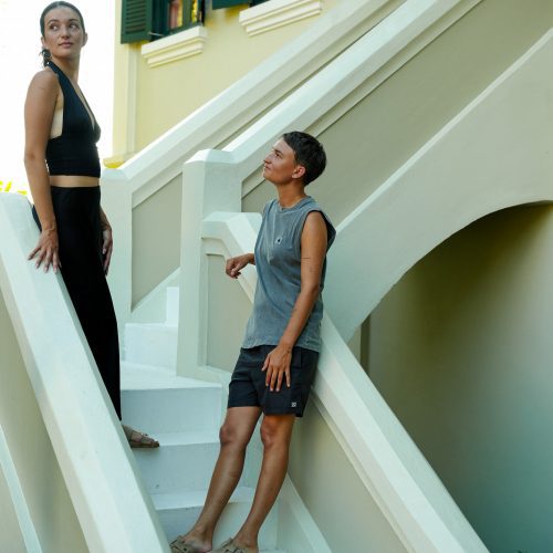 Deux personnes sur un escalier blanc devant une façade coloniale du Villa Maly à Luang Prabang.