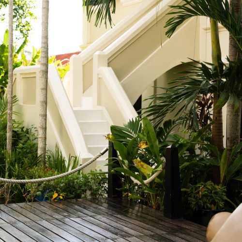 Vue sur l’architecture coloniale du Villa Maly à Luang Prabang, entourée d’un jardin tropical luxuriant et d’une terrasse en bois, photographie par chloeandaurore.